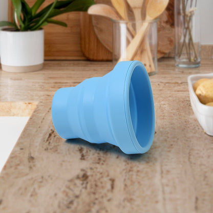 Flexible silicone travel mug in purple, held by hand, highlighting its ergonomic design.
